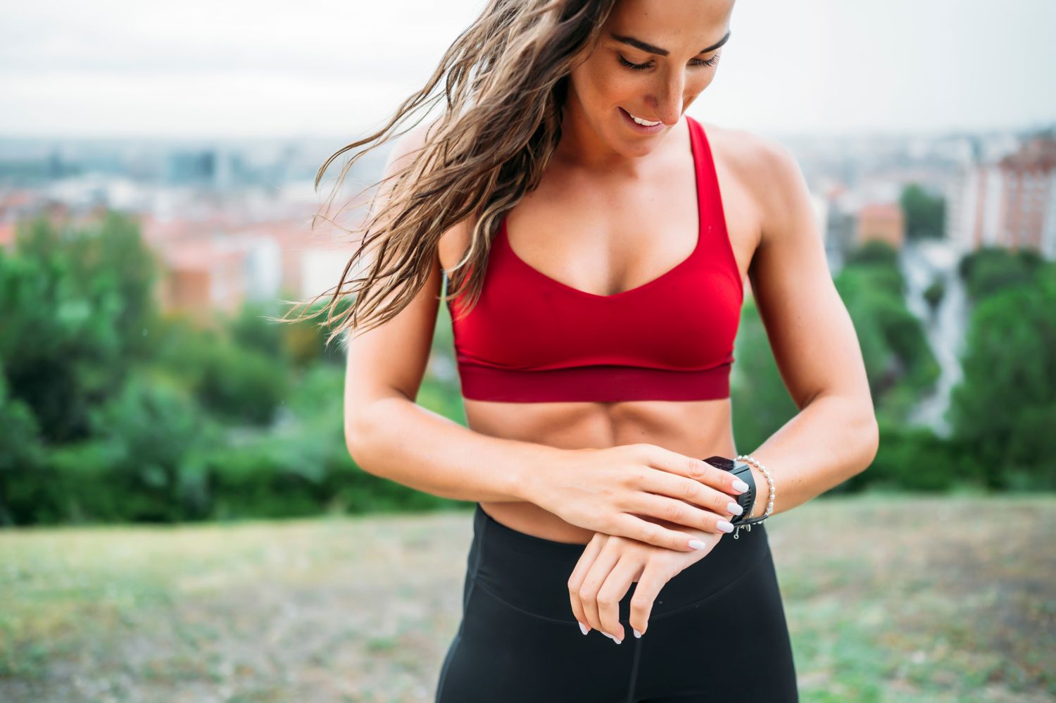Mujer hace deporte en una montaña, mientras mira su smartband